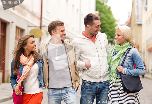 Image of group of smiling friends walking in the city