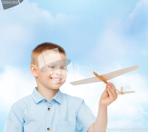 Image of smiling little boy holding a wooden airplane model