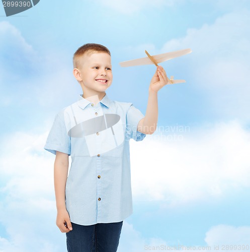 Image of smiling little boy holding a wooden airplane model