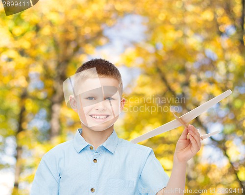 Image of smiling little boy holding a wooden airplane model