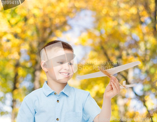 Image of smiling little boy holding a wooden airplane model