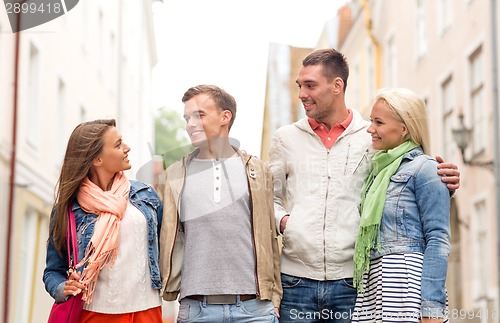Image of group of smiling friends walking in the city