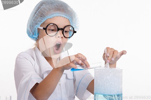 Image of Chemist pours blue liquid in the flask
