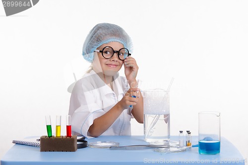 Image of Chemist pours the blue liquid in flask