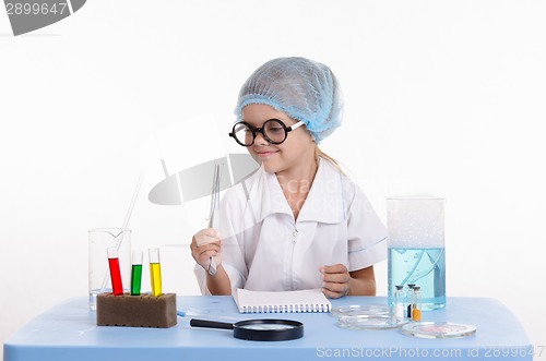 Image of Girl chemist holding tweezers