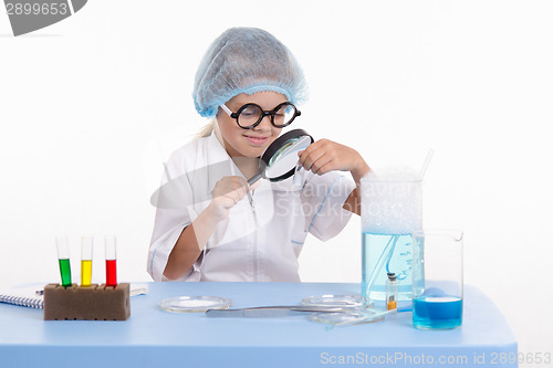 Image of Chemist looking through a magnifying glass on white powder