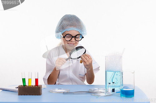 Image of Chemist looking through a magnifying glass on powder