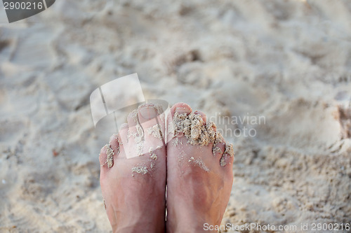Image of beach with feet of the man on sand