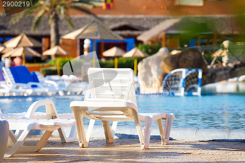 Image of sunloungers on swimming pool 