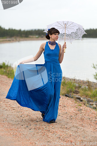 Image of Young slim girl in a blue dress with an umbrella