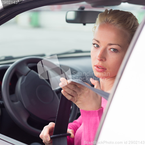 Image of Beautiful woman fastening seat belt.