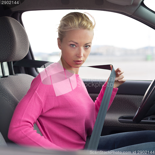 Image of Beautiful woman fastening seat belt.