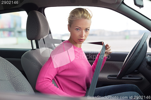 Image of Beautiful woman fastening seat belt.