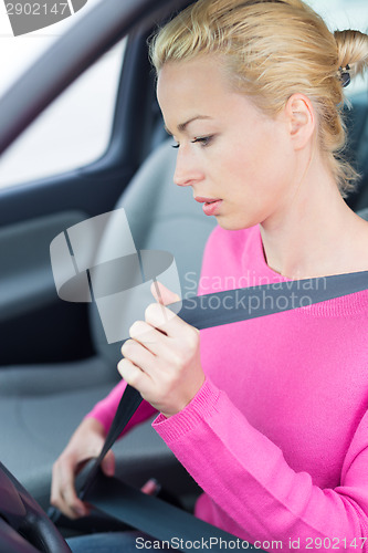 Image of Beautiful woman fastening seat belt.