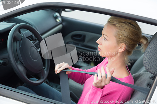 Image of Beautiful woman fastening seat belt.