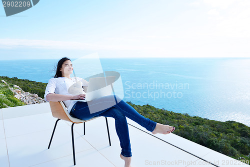 Image of relaxed young woman at home working on laptop