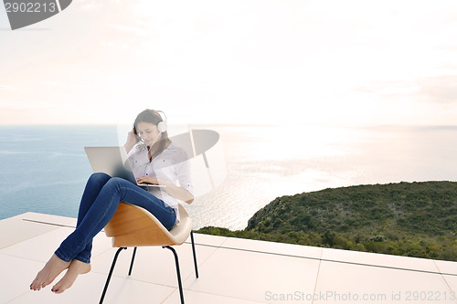 Image of relaxed young woman at home working on laptop