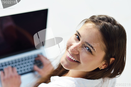 Image of relaxed young woman at home working on laptop computer