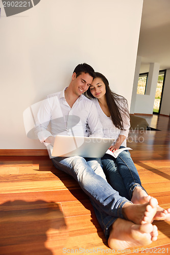 Image of relaxed young couple working on laptop computer at home