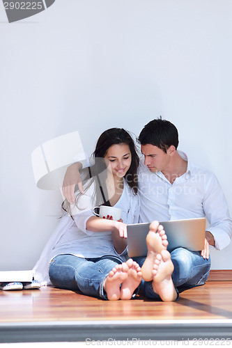 Image of relaxed young couple working on laptop computer at home