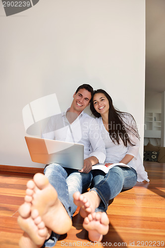 Image of relaxed young couple working on laptop computer at home