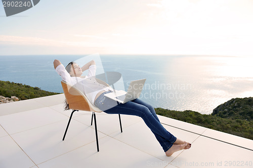 Image of relaxed young woman at home working on laptop
