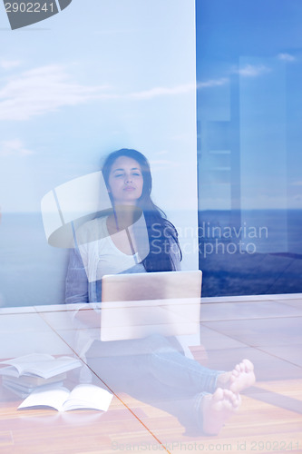 Image of relaxed young woman at home working on laptop computer