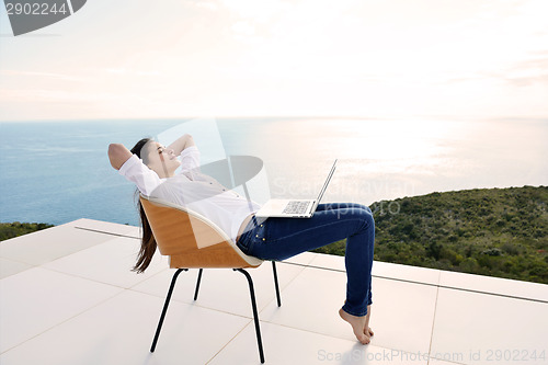 Image of relaxed young woman at home working on laptop