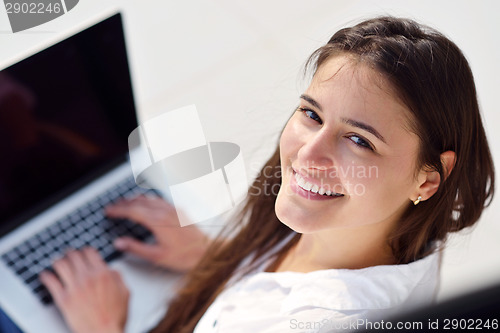 Image of relaxed young woman at home working on laptop computer