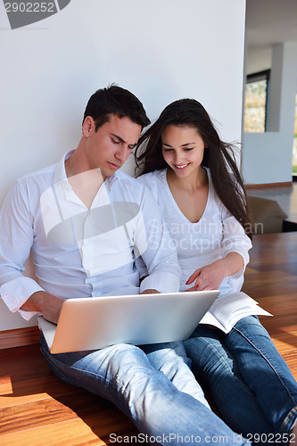 Image of relaxed young couple working on laptop computer at home