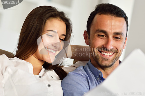Image of relaxed young couple working on laptop computer at home
