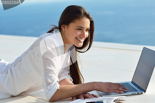 Image of relaxed young woman at home working on laptop computer