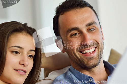 Image of relaxed young couple working on laptop computer at home