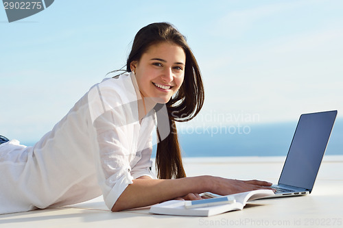 Image of relaxed young woman at home working on laptop computer