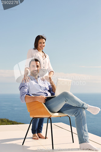 Image of relaxed young couple working on laptop computer at home