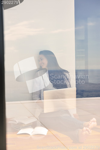 Image of relaxed young woman at home working on laptop computer