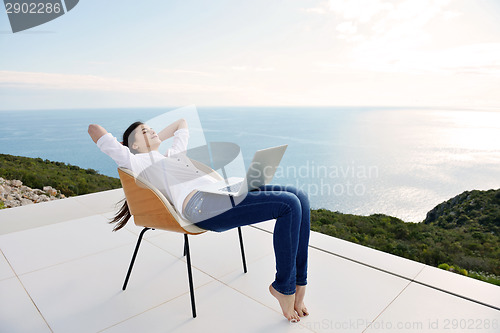 Image of relaxed young woman at home working on laptop