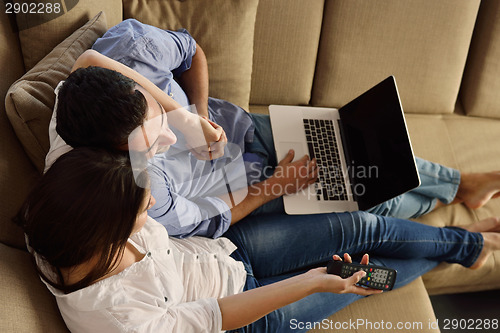 Image of relaxed young couple working on laptop computer at home