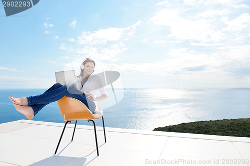 Image of relaxed young woman at home working on laptop