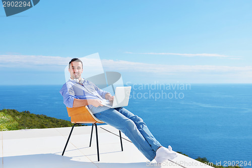 Image of relaxed young man at home on balcony