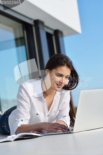 Image of relaxed young woman at home working on laptop computer