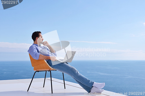 Image of relaxed young man at home on balcony