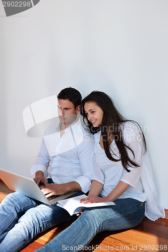 Image of relaxed young couple working on laptop computer at home