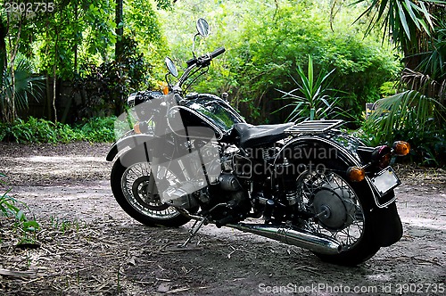 Image of vintage black motorcycle in subtropical setting