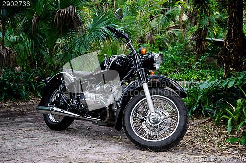 Image of vintage black motorcycle in tropical setting