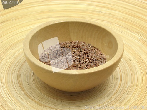 Image of Wooden bowl with flaxseed on bamboo plate