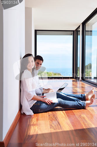 Image of relaxed young couple working on laptop computer at home