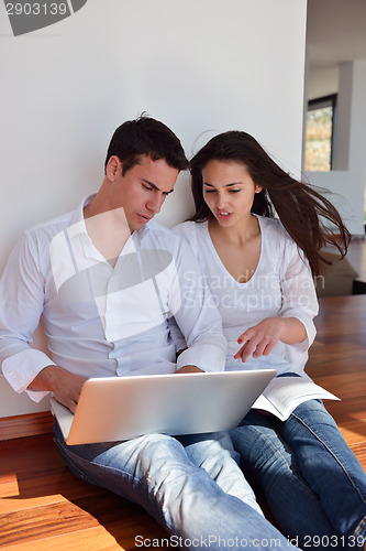 Image of relaxed young couple working on laptop computer at home