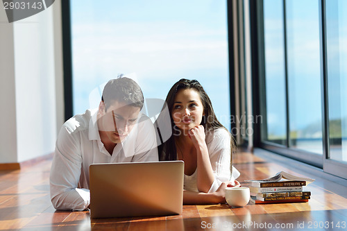 Image of relaxed young couple working on laptop computer at home