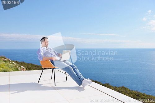 Image of relaxed young man at home on balcony